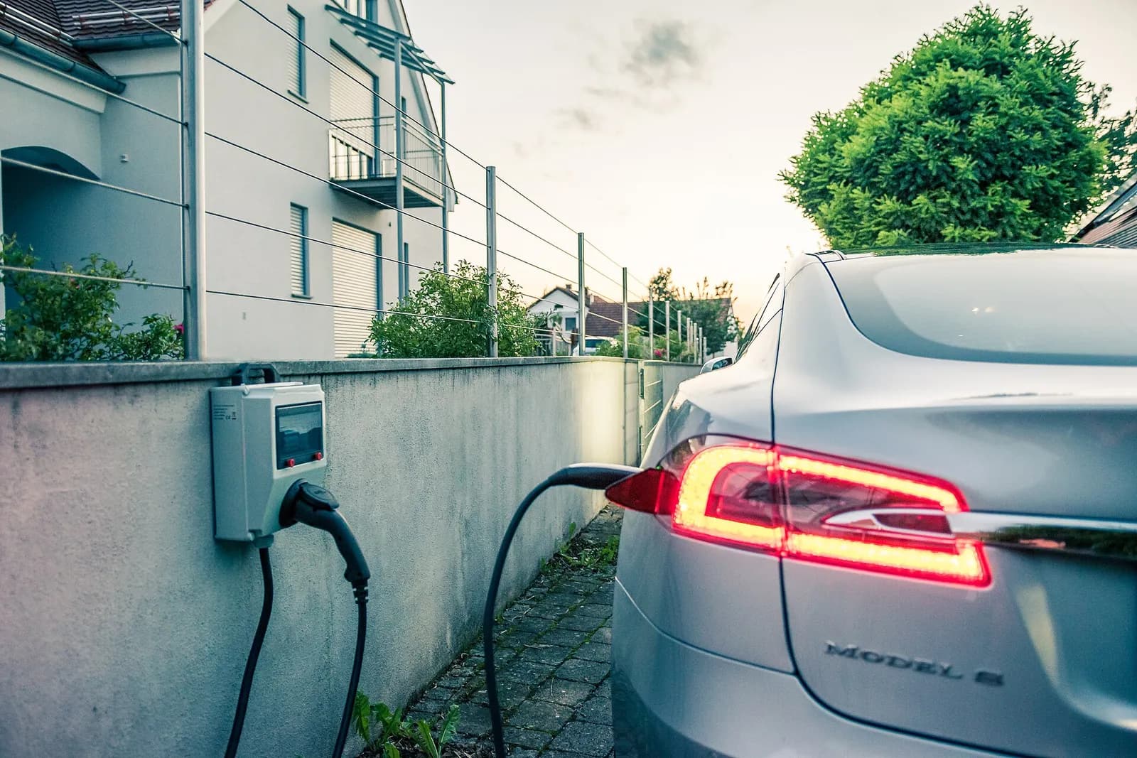 Voiture électrique en charge sur une borne murale contre une maison